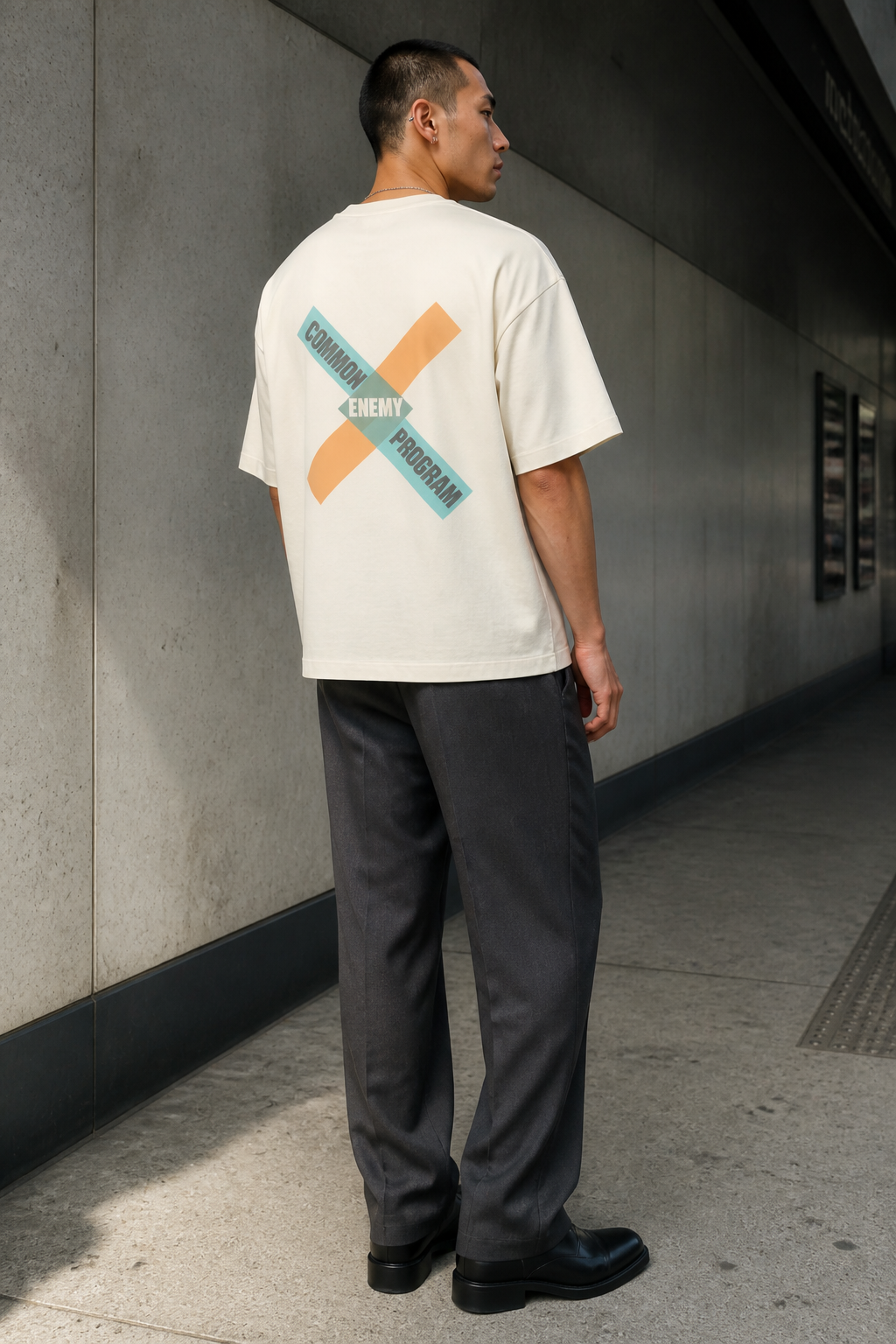 Model wearing the 3o1d COMMON ENEMY PROGRAM oversized T-shirt in Cream, back graphic.